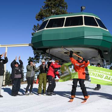 Una foto del día de apertura de la temporada de invierno 2025/26 de la estación de esquí Bear Mountain: alguien está cortando una pancarta mientras lleva puestos los esquís.