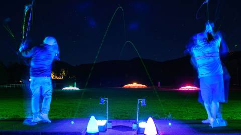 Una foto del Glow Golf de Bear Mountain Resort, la bola verde de colores brillantes volando por el aire.