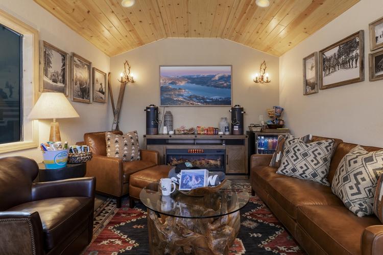 Una foto del interior de la suite IKON Pass, donde hay una chimenea eléctrica, sofás, una mininevera, una mesa de centro y luces acogedoras.