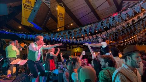 Se reunió una gran multitud para ver a un grupo tocando en directo en el escenario del Oktoberfest; uno de los músicos se acerca a alguien del público.