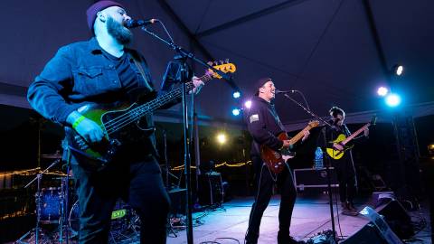 Una banda tocando en el escenario durante el Gran Premio de Motocross: tocan la guitarra mientras cantan por los micrófonos.