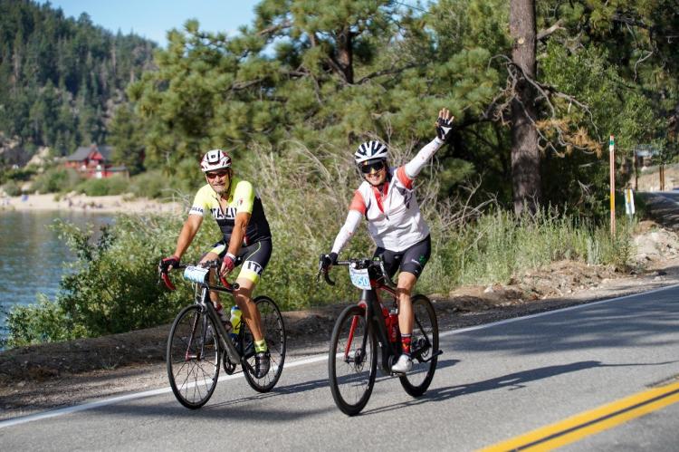Dos ciclistas saludan durante su recorrido en bicicleta por el Tour de Big Bear en Big Bear Lake, CA