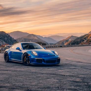Un Porsche azul junto a una sinuosa carretera de montaña. Promocionando el evento Porsche timeline en Big Bear Lake.