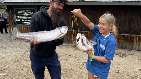 Un padre y su hija sostienen la trucha que pescaron durante el Torneo de Truchas Fishin' For $50K 2023 en Big Bear Lake.