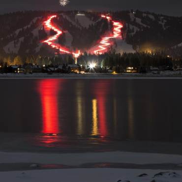 Las luces rojas iluminan una estación de esquí oscura de Snow Summit durante el desfile anual de antorchas de Nochevieja en Big Bear, California.