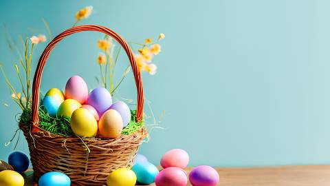 Foto de archivo: Una cesta de Pascua sobre una mesa con huevos de colores y flores amarillas. La pared de fondo es de color turquesa.