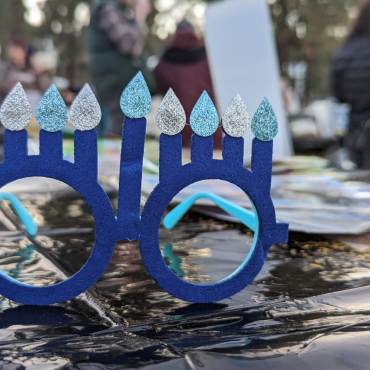 Un par de gafas azules con ocho velas de Janucá sobre una mesa durante una celebración de Janucá en Big Bear Lake, California.