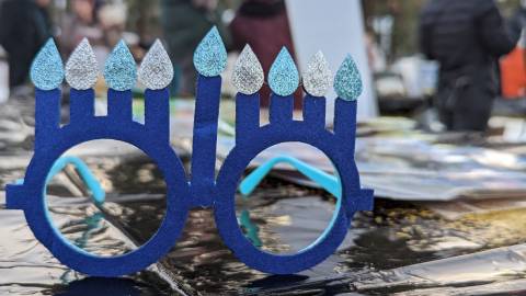 Un par de gafas azules con ocho velas de Janucá sobre una mesa durante una celebración de Janucá en Big Bear Lake, California.