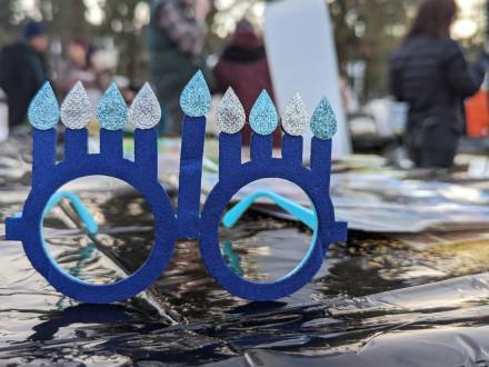 Un par de gafas azules con ocho velas de Janucá sobre una mesa durante una celebración de Janucá en Big Bear Lake, California.