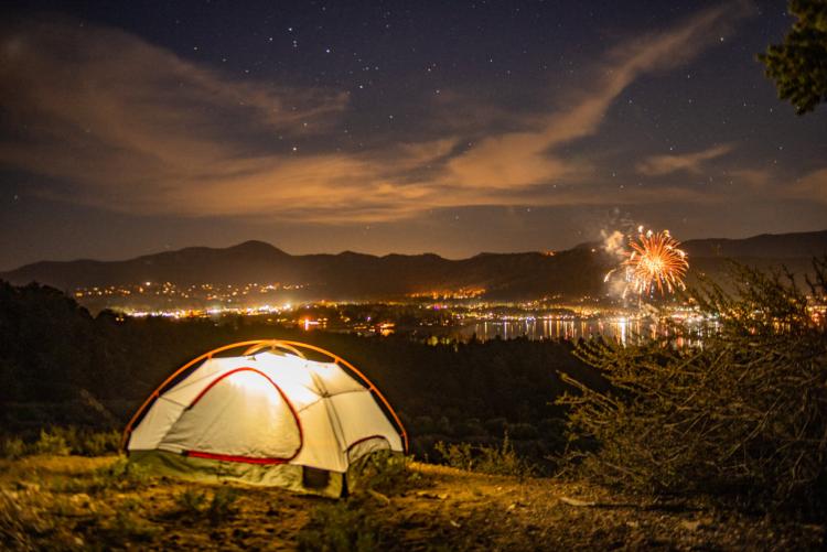 Una tienda de campaña iluminada en una colina con vistas a Big Bear y al espectáculo de fuegos artificiales del 4 de julio.