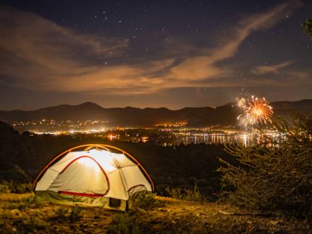 Una tienda de campaña iluminada en una colina con vistas a Big Bear y al espectáculo de fuegos artificiales del 4 de julio.
