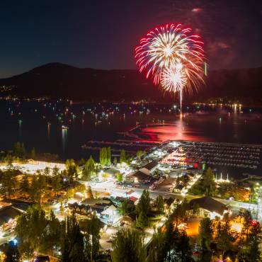 Unos fuegos artificiales rojos explotan sobre Big Bear Lake el 4 de julio. Las luces de los barcos y de la ciudad son visibles en esta escena nocturna.
