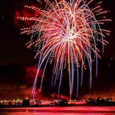 Fuegos artificiales de color carmesí llenan el cielo nocturno y se reflejan en el agua de Big Bear Lake, California, durante el espectáculo de fuegos artificiales del 4 de julio.