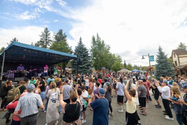 Una foto tomada durante la serie de conciertos de verano, la banda está tocando en el escenario frente a una gran multitud situada en el Village.