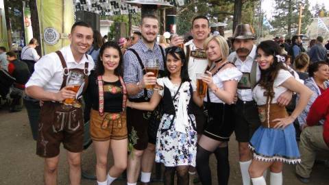 Los animados asistentes se visten con trajes tradicionales en la Oktoberfest y sostienen jarras de cerveza.