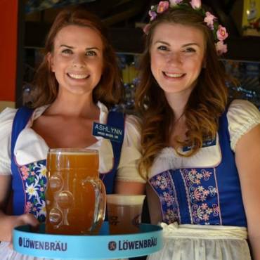 Camareras sonríen a la cámara y sirven cerveza en el Oktoberfest con trajes festivos en Big Bear Lake, CA