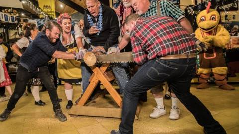 Dos hombres cortan un tronco con una sierra para dos personas en la competición de aserrado de troncos de la Oktoberfest.