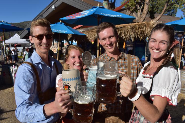 Un grupo de cuatro personas posa para una foto con jarras de cerveza en la mano, vestidos con la ropa tradicional de la Oktoberfest.