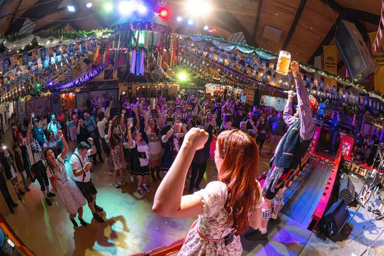 Plano general del Oktoberfest del lago Big Bear: dos miembros de la banda, en el escenario, levantan las manos ante la gran multitud que tienen delante.