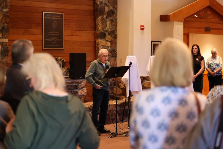 Foto tomada de la ceremonia de entrega de premios durante el concurso de artes Plein Air, la multitud escuchando la presentación del anciano.