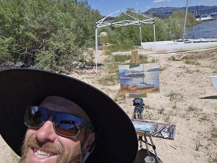 Carga social de un artista de su pintura durante el concurso Plein Air, su pintura representa el Big Bear Shoreline.