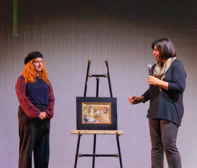 Una foto de la ceremonia de entrega de premios Plein Air, en la que se ve a Lisa Mozzini-McDill hablando con el ganador del segundo puesto del concurso.