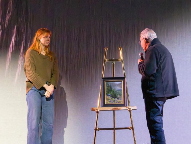 Una foto de la ceremonia de entrega de premios Plein Air, en la que se ve a John Budicin hablando con el ganador del primer premio del concurso.