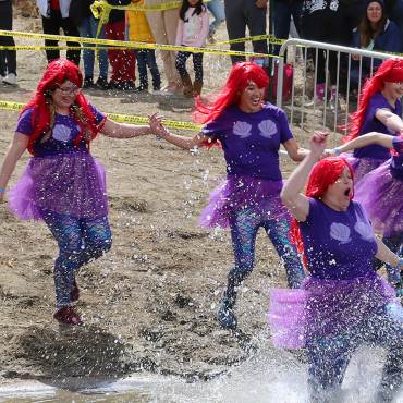 Los participantes disfrazados de sirena corren hacia las gélidas aguas del lago Big Bear durante la inmersión polar.