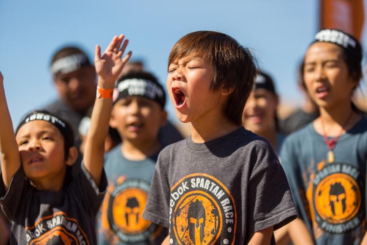Una multitud de jóvenes con camisetas de la Spartan Race animan a los competidores en el Spartan Trifecta Weekend en Big Bear Lake, California.