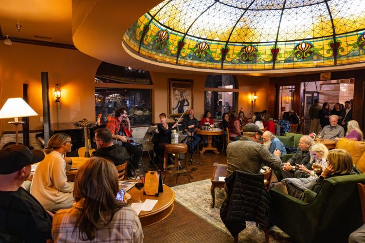 Una foto del Tiffany's Bistro en el Chateau Big Bear: hay músicos tocando en directo ante un numeroso público.