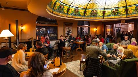 Una foto del Tiffany's Bistro en el Chateau Big Bear: hay músicos tocando en directo ante un numeroso público.