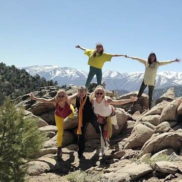 Una foto de 5 mujeres estirando durante Big Bear Lake Yoga Fest, las montañas cubiertas de nieve visibles en la distancia.