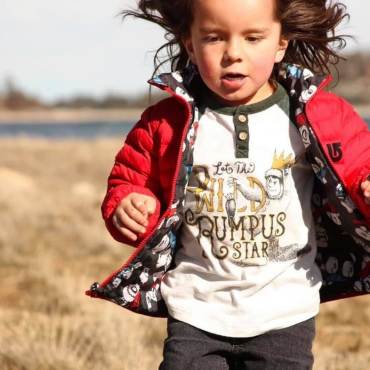 Un niño con chaqueta roja corre por la hierba cerca de Big Bear Lake.