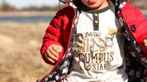 Un niño con chaqueta roja corre por la hierba cerca de Big Bear Lake.