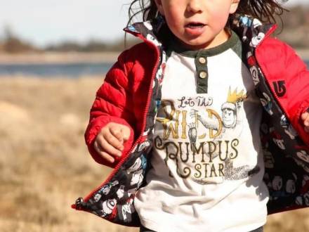 Un niño con chaqueta roja corre por la hierba cerca de Big Bear Lake.