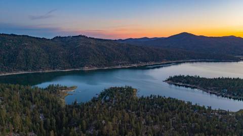Una foto de Big Bear Lake tomada durante una puesta de sol de la Hora Dorada, el lago y las montañas visibles en la distancia.