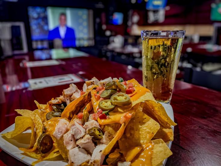 Un plato de nachos de aperitivo sobre una mesa con un vaso de cerveza rubia en el Village Sports Bar de Big Bear Lake, California.