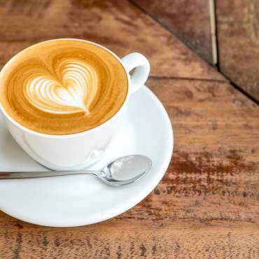 Una taza de café coronada con espuma en forma de corazón.
