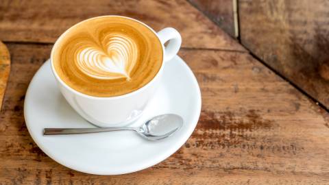 A cup of coffee topped with foamy coffee art in the shape of a heart.