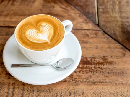 A cup of coffee topped with foamy coffee art in the shape of a heart.