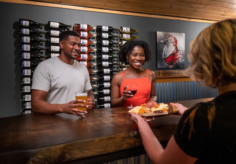 Una pareja sonríe mientras les sirven un aperitivo con sus bebidas en Barrel 33 en Big Bear Lake, California.