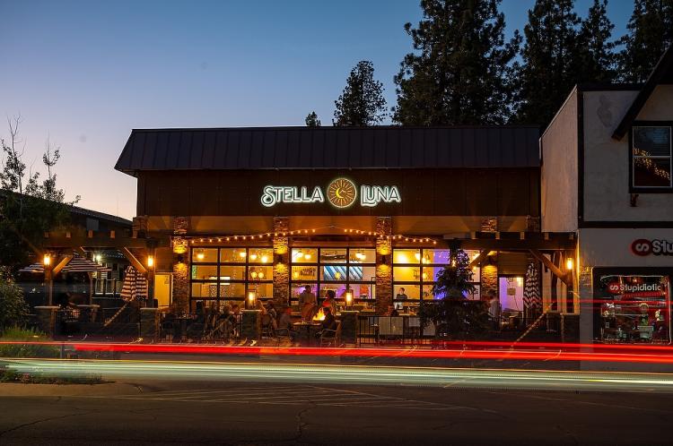 Fachada exterior del restaurante Stella Luna en Big Bear Lake, California. Es de noche y pasa un coche.
