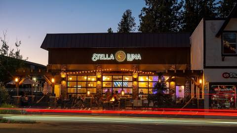 Fachada exterior del restaurante Stella Luna en Big Bear Lake, California. Es de noche y pasa un coche.