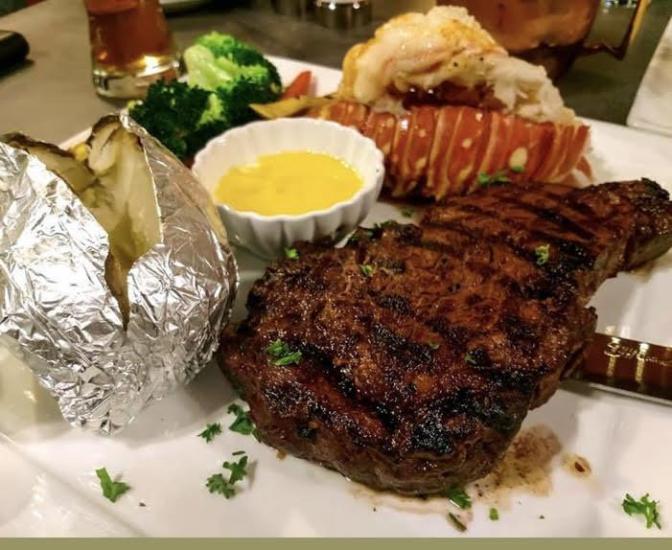 Una foto de un plato de surf and turf en Santana & Mavericks, en el plato hay un filete, una cola de langosta, mantequilla y brócoli.