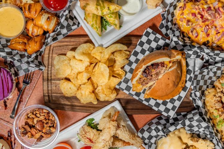 Vista desde arriba de la comida servida en la sala Moonridge: hay aperitivos alrededor de una hamburguesa con forma de platillo volante.