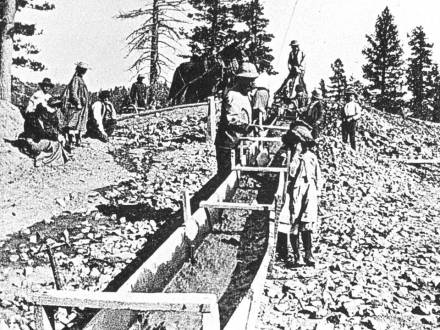 Fotografía en blanco y negro de buscadores de oro en un arroyo artificial.