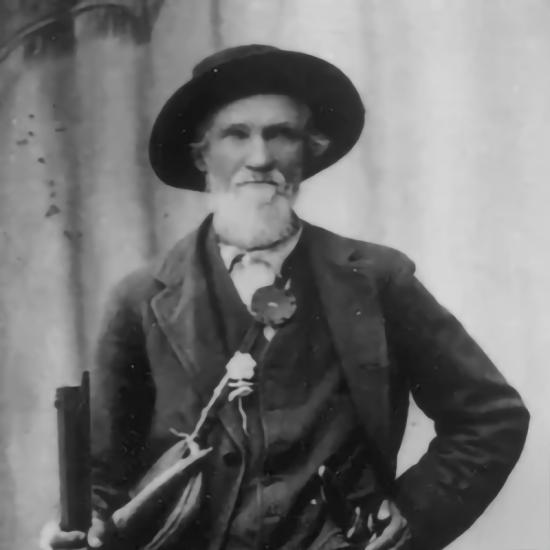 Una vieja fotografía en blanco y negro de William Francis «Grizzly Bill» Holcomb: lleva un sombrero de buscador de oro y un abrigo.