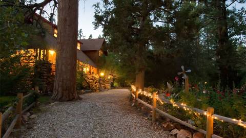 Un camino con una valla decorada con guirnaldas de luces que conduce a un gran Bed & Breakfast en Big Bear Lake, California.
