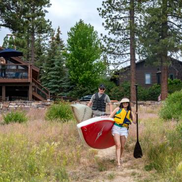 Una pareja lleva tablas de paddle al lago Big Bear desde su casa de alquiler vacacional frente al lago.