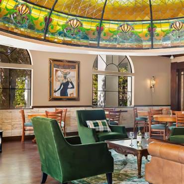 Una foto del interior del Tiffany's Bistro en el Chateau Big Bear: se ven sillas de tela y de cuero bajo su cúpula Tiffany.